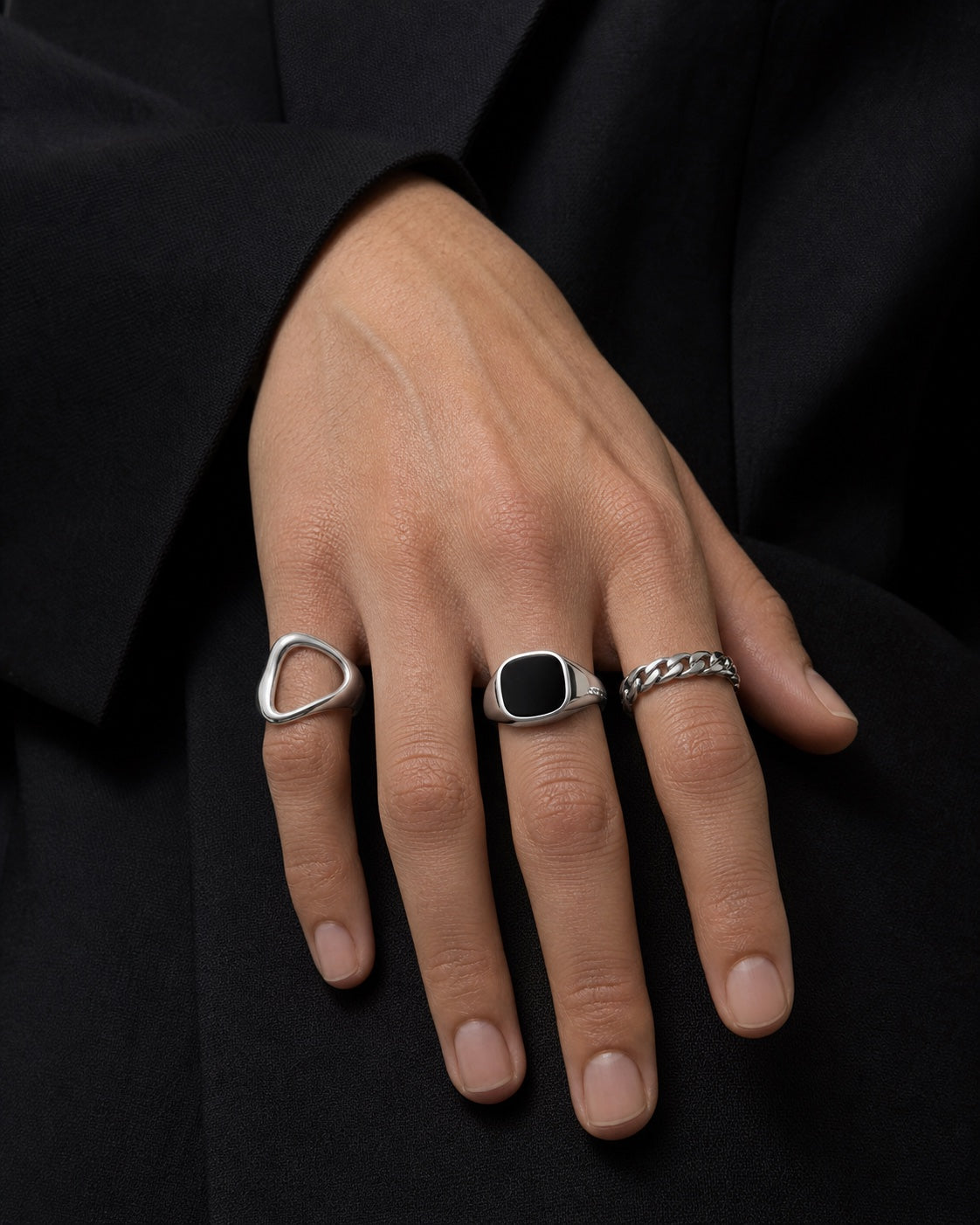 Hand wearing three sculptural silver rings