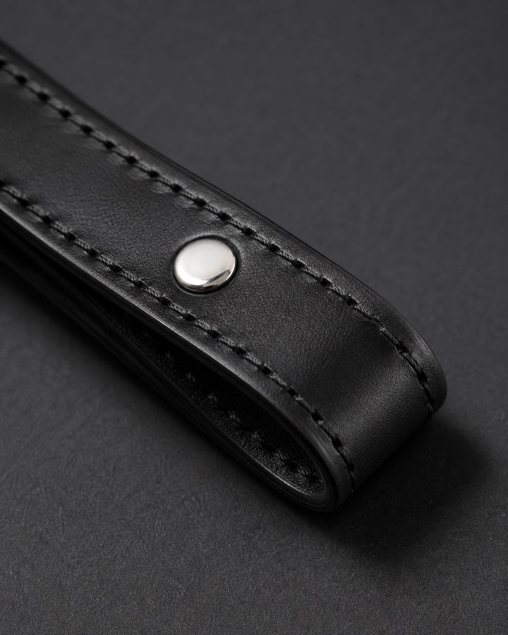 Macro detail of premium black leather, stitching and silver rivet